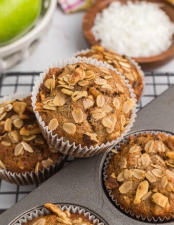 Several morning glory muffins are placed in a baking pan and on a wire cooling rack.