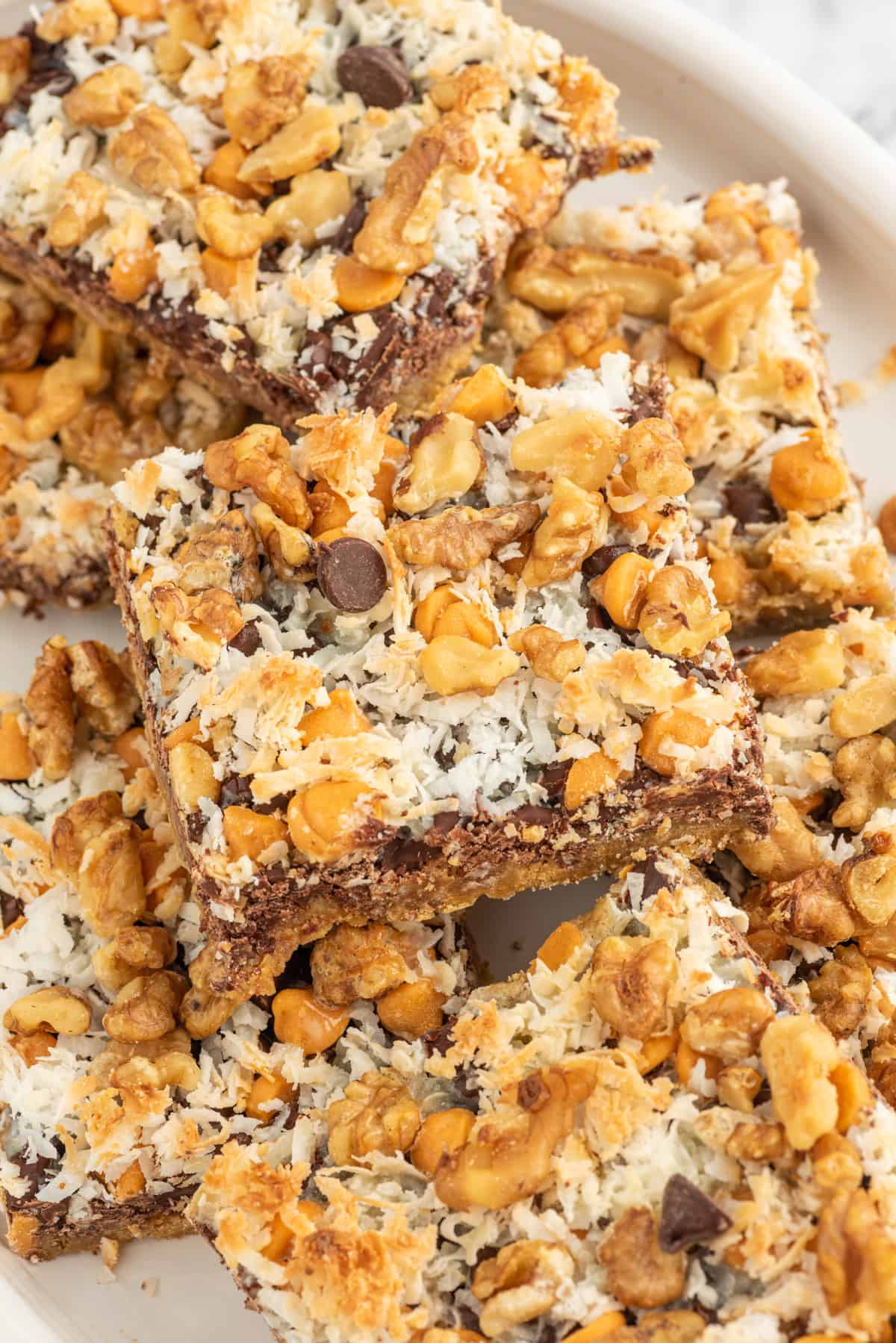 Several magic bars are stacked on top of one another on a serving plate.