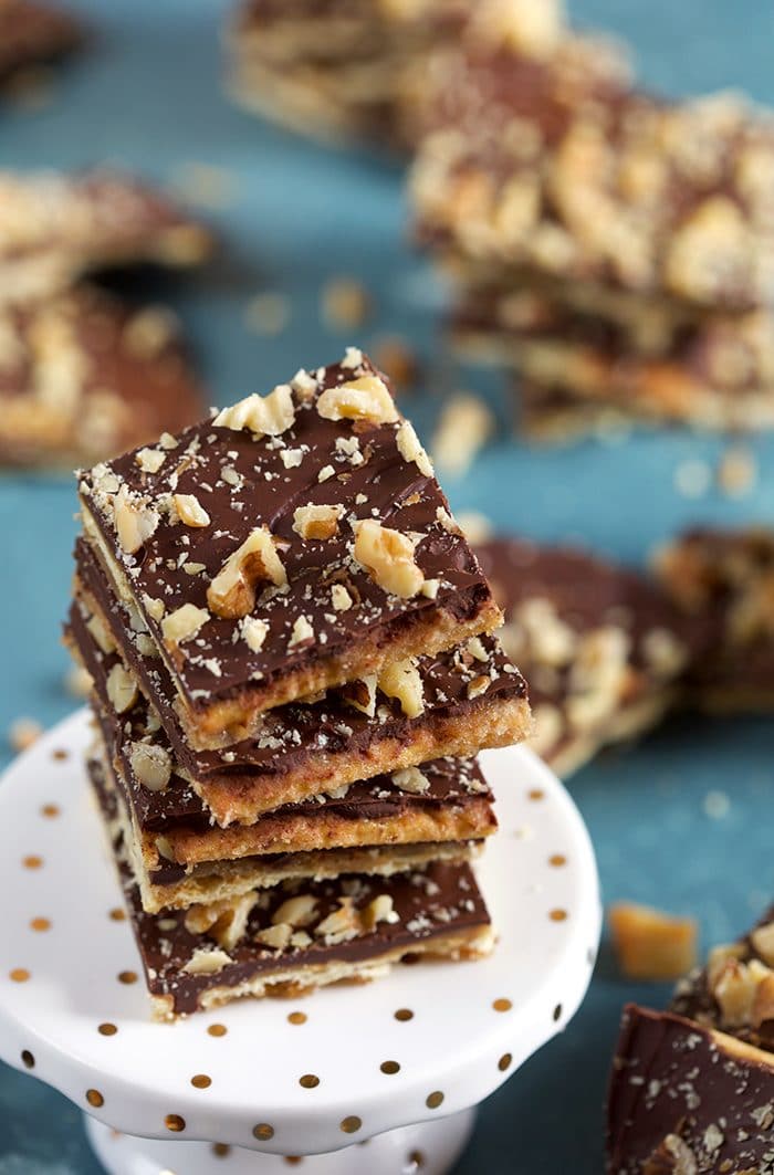 Stack of saltine cracker toffee with walnuts on a white cupcake stand.
