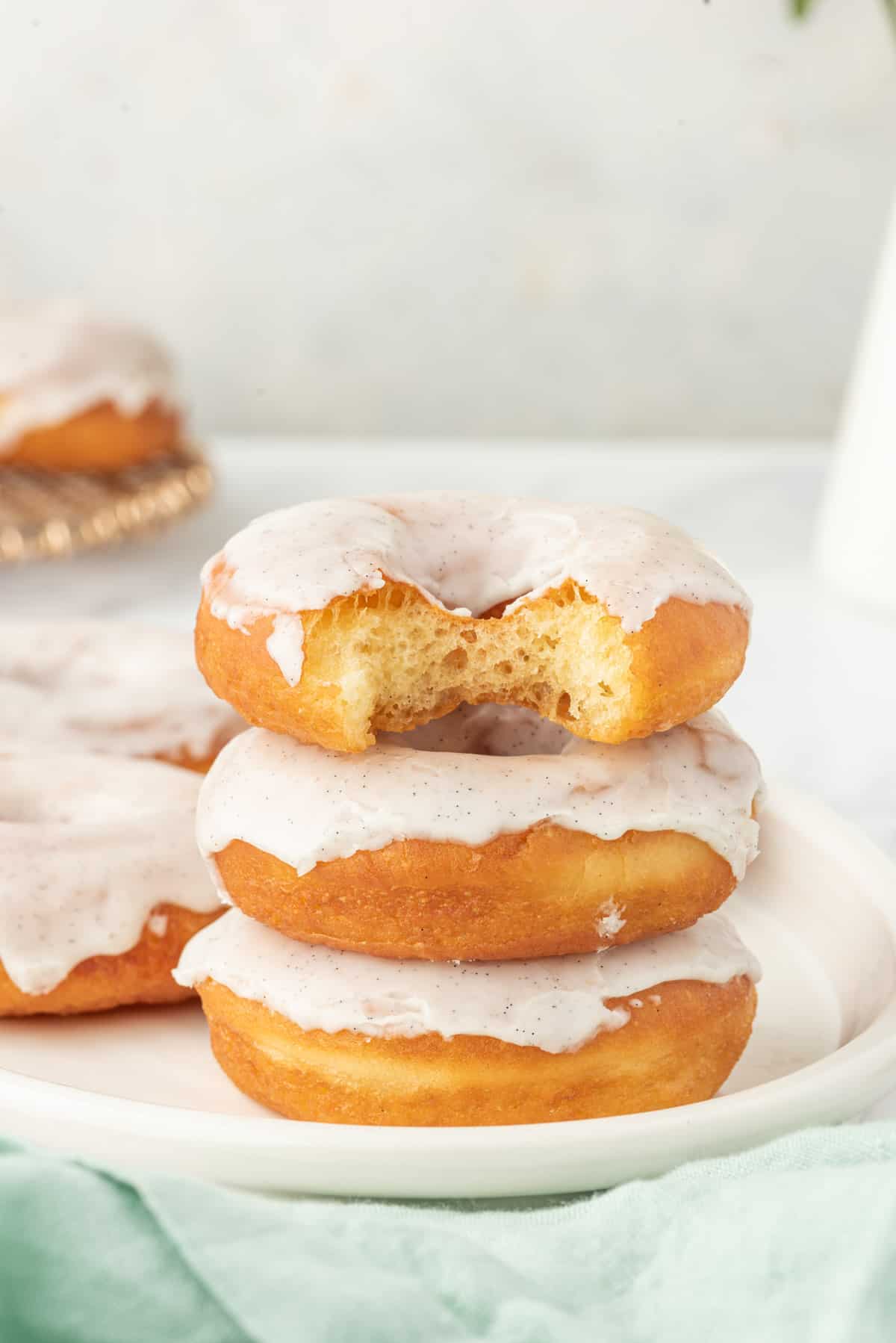 A stack of three donuts is presented on a white plate.