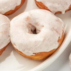 Several glazed donuts are placed on a white plate.
