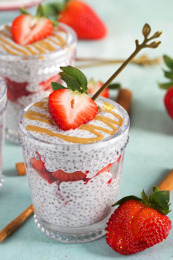Chia Pudding layered in a glass with strawberries and a gold spoon.