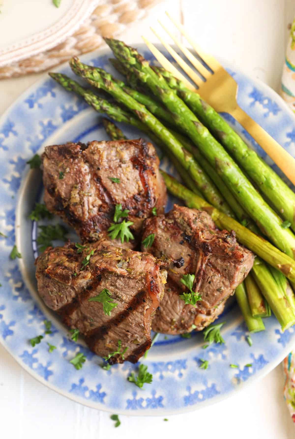 Overhead view of grilled lamb loin chops on plate with asparagus