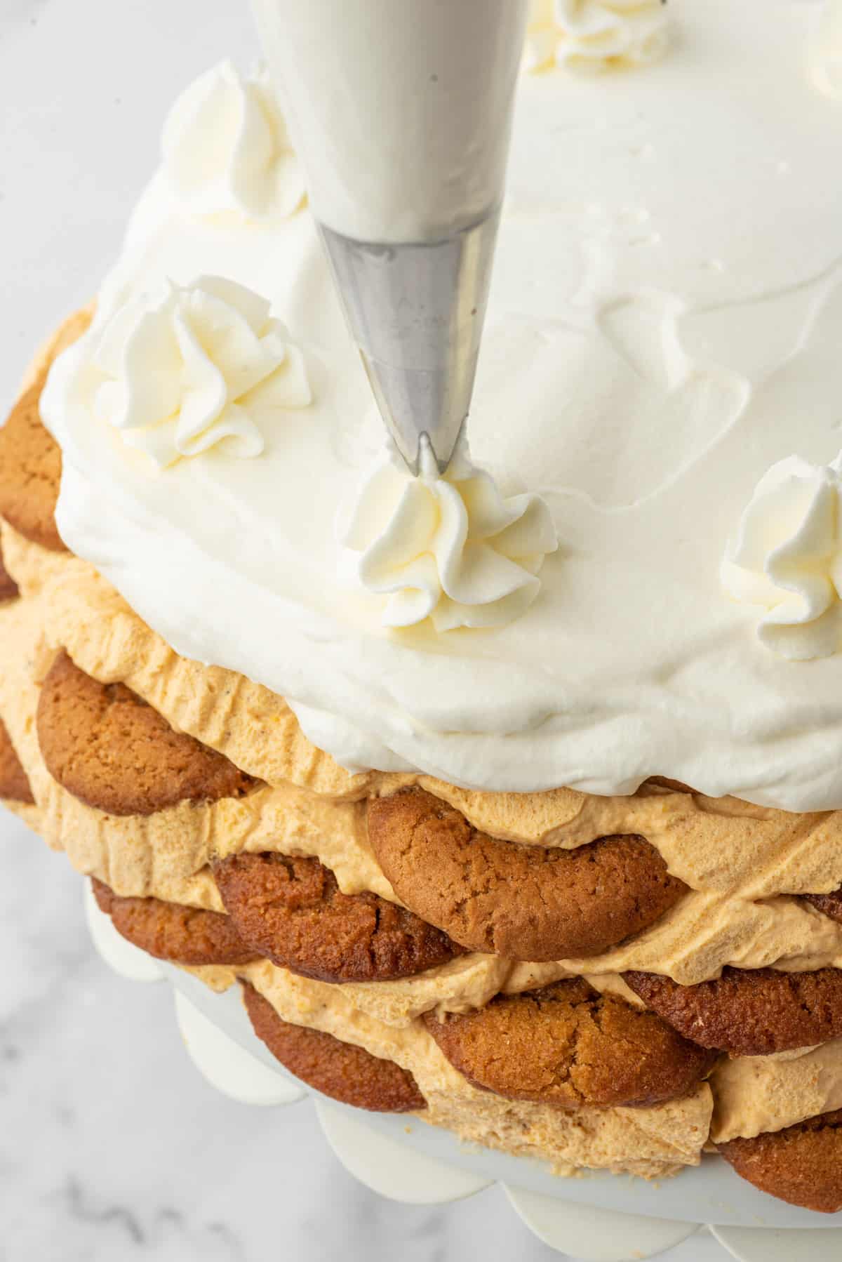 Whipped cream is being piped onto an icebox cake.