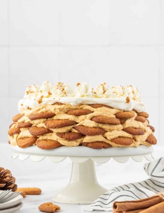 A layered pumpkin icebox cake is presented on a white cakestand.