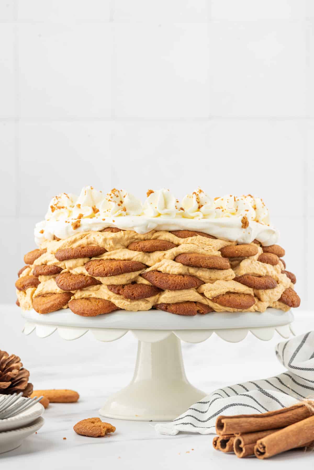 A layered pumpkin icebox cake is presented on a white cakestand. 
