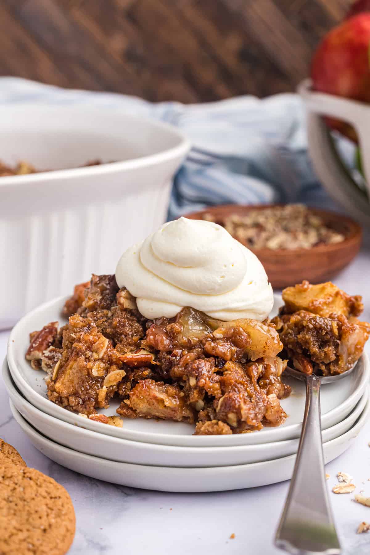 A dollop of whipped cream is on top of a serving of gingersnap apple crisp.