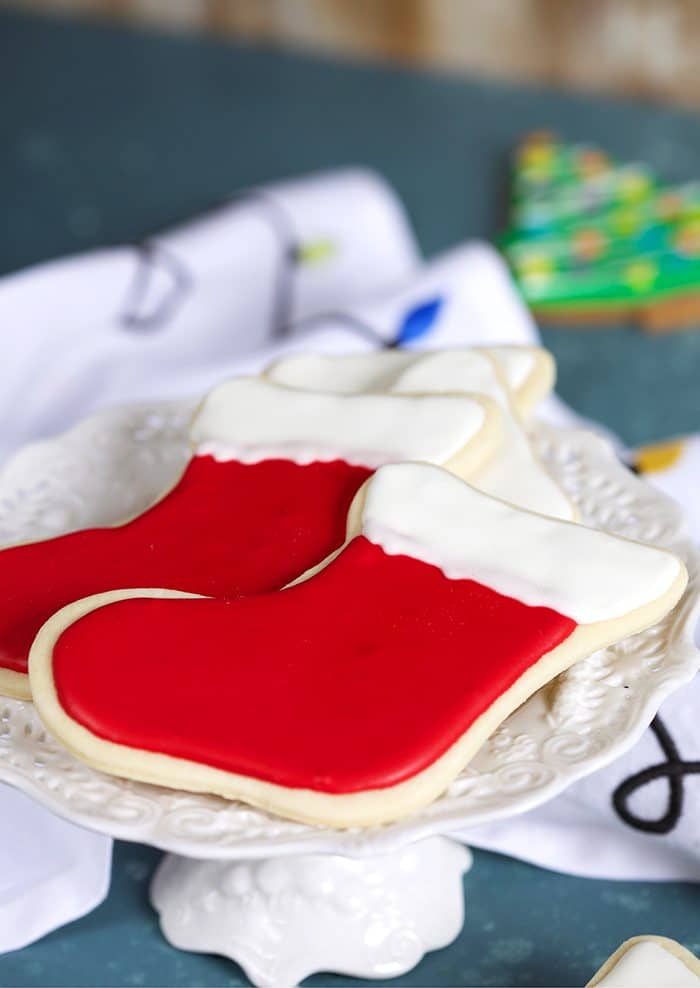 Two red stocking cookies on a white cake plate.