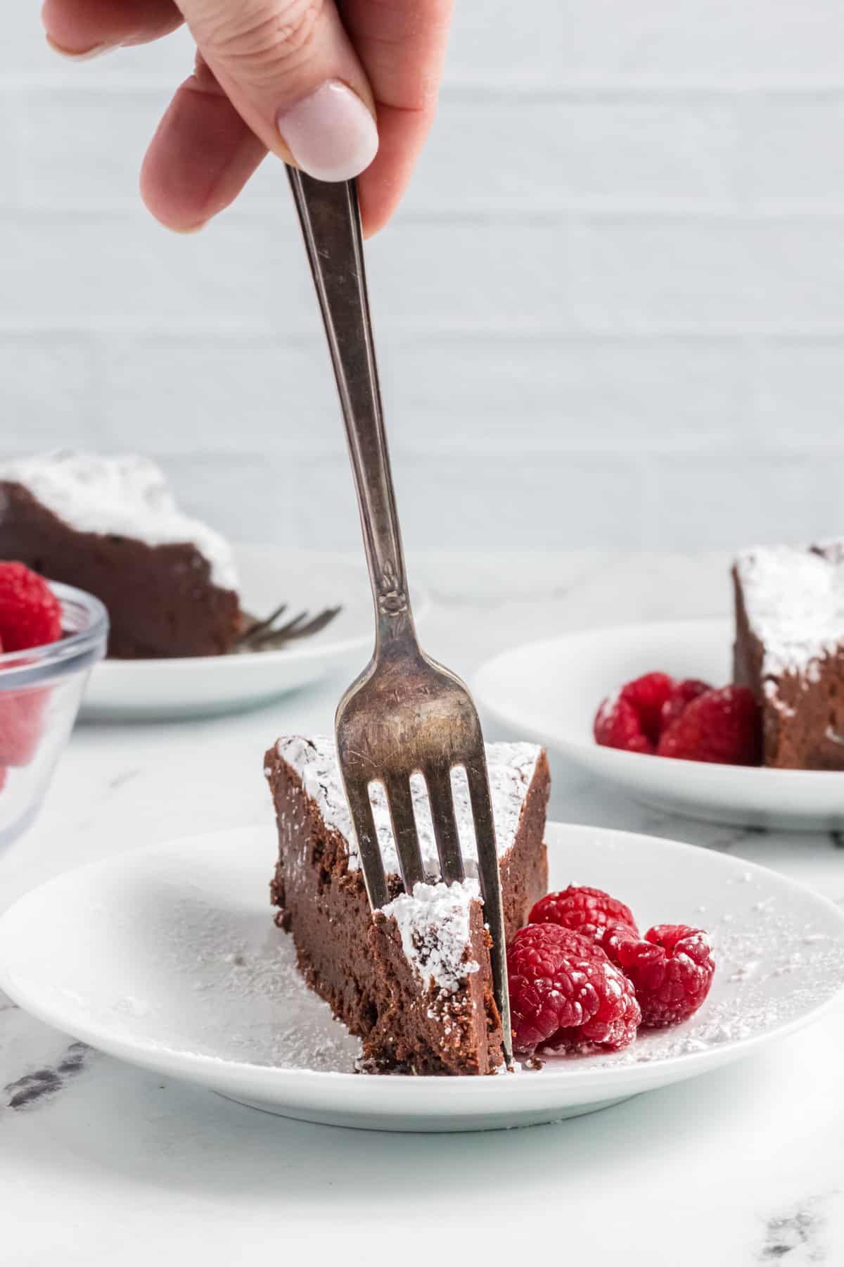 A fork is digging into a slice of chocolate cake.
