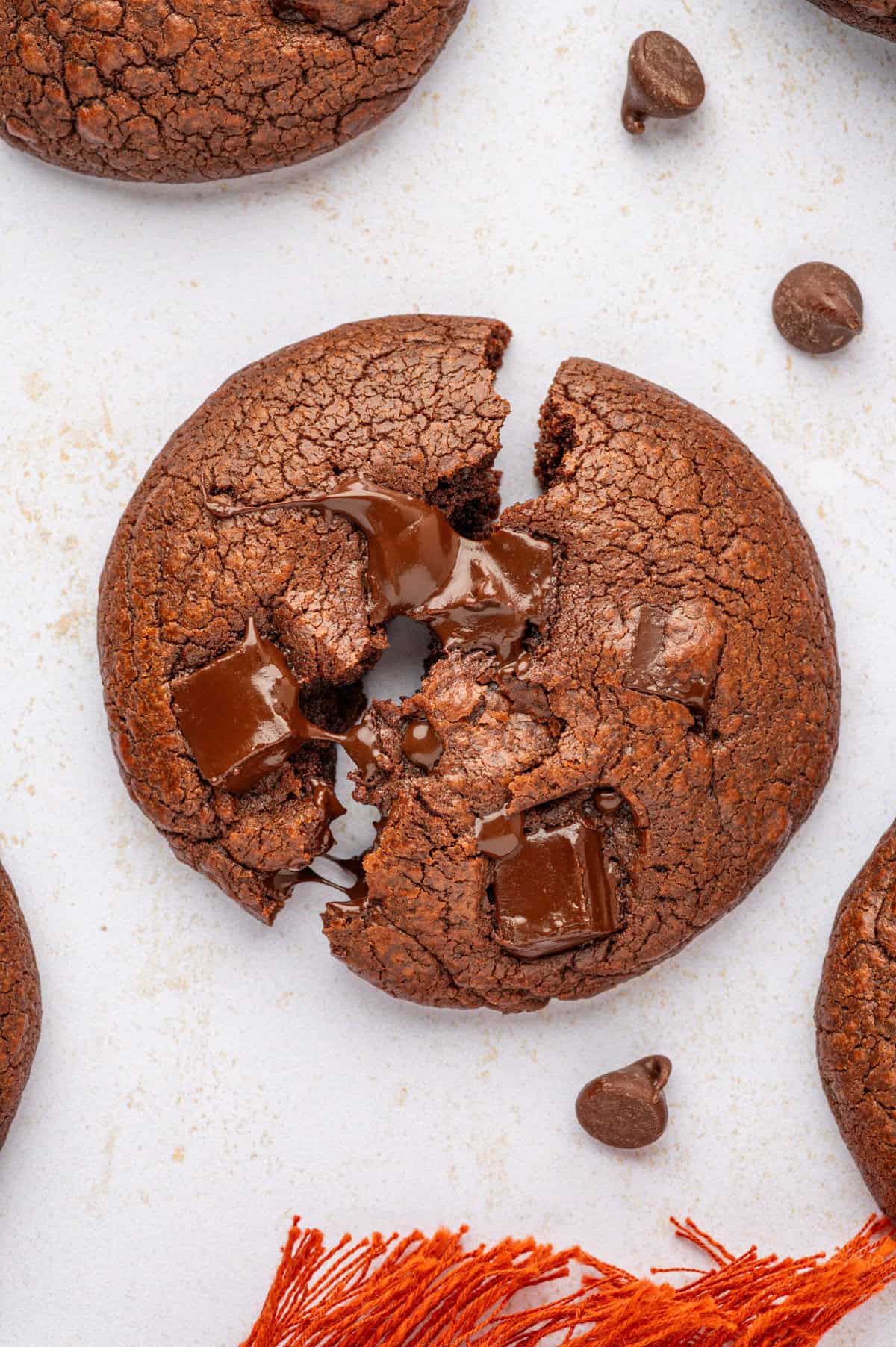 Overhead view of double chocolate chip cookie broken in half to show melting chocolate chunks