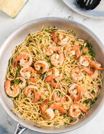 Shrimp scampi is being cooked in a large skillet.