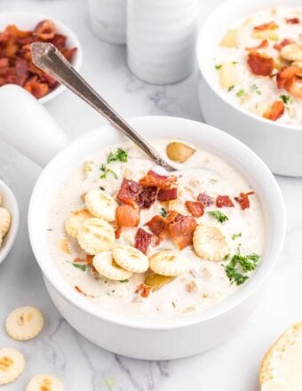 A bowl of clam chowder is topped with fried bacon bits.