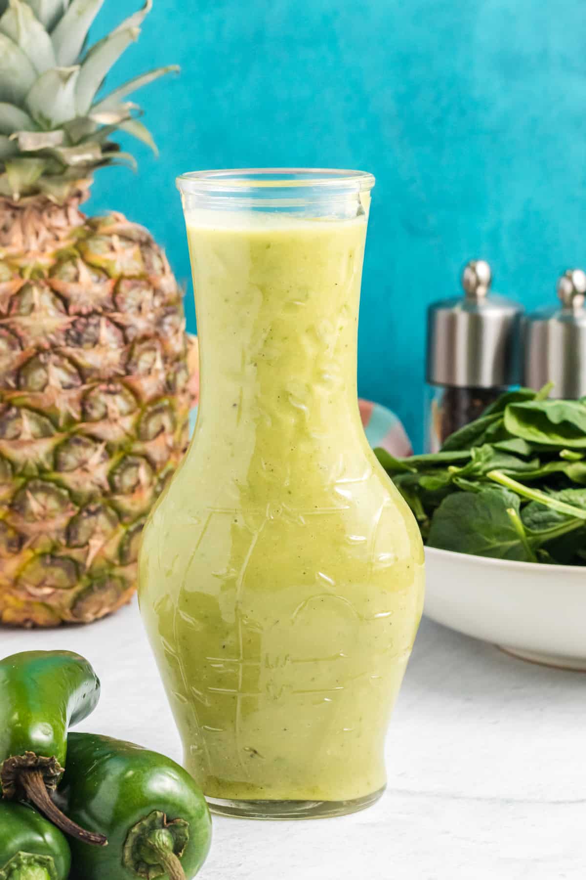 A large glass container is filled with green salad dressing.