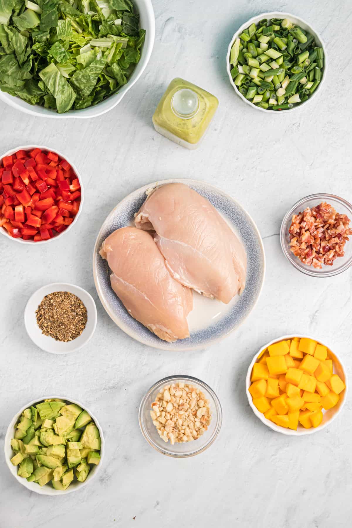 The ingredients for cobb salad are placed on a white countertop.