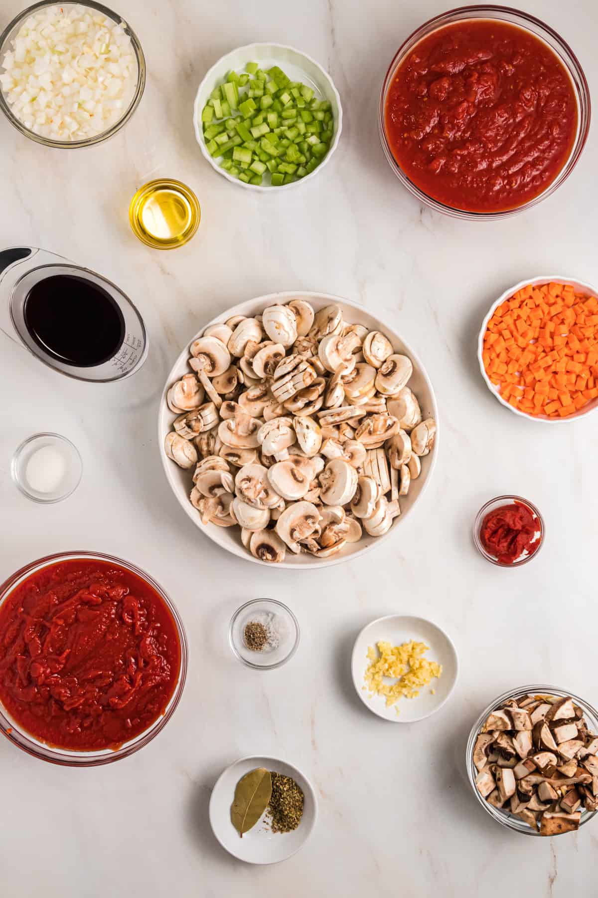 The ingredients for mushroom bolognese are spread out on a white surface.