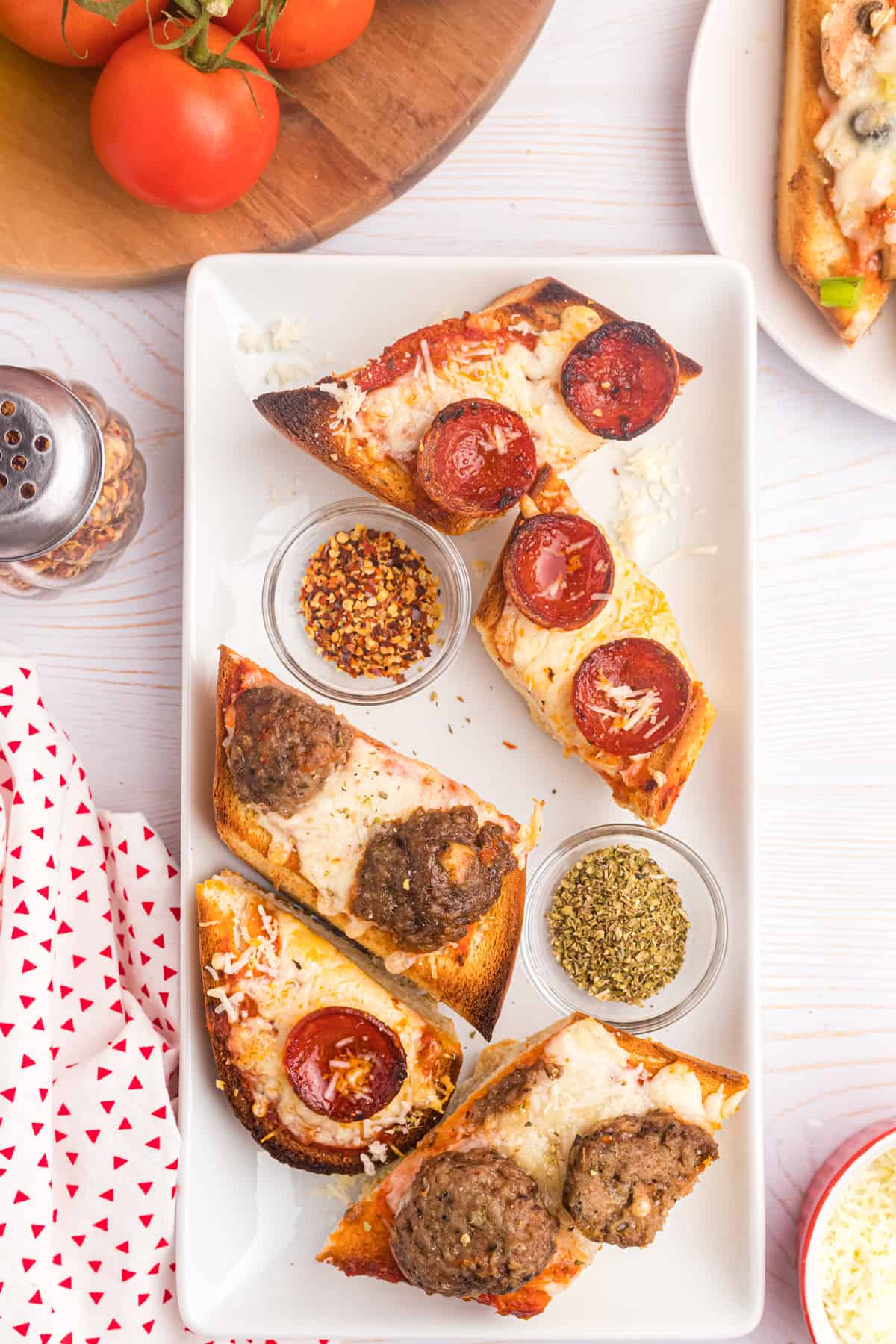 Several pieces of french bread pizza are placed on a white serving platter.