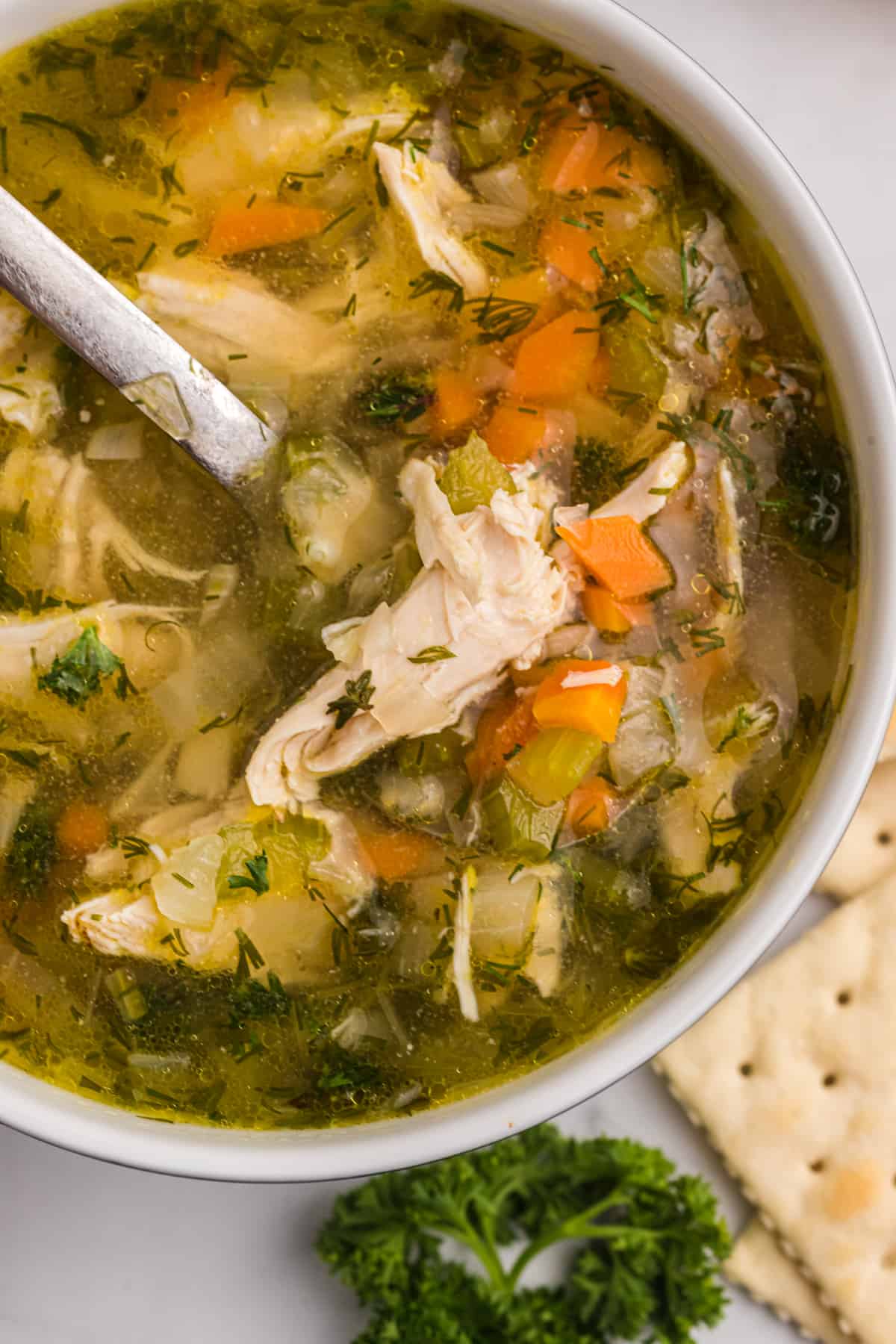 pot filled with chicken soup with a ladle inside.