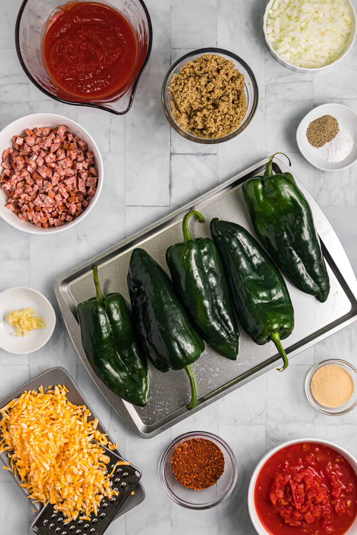 The ingredients for stuffed poblano peppers are presented on a white surface.