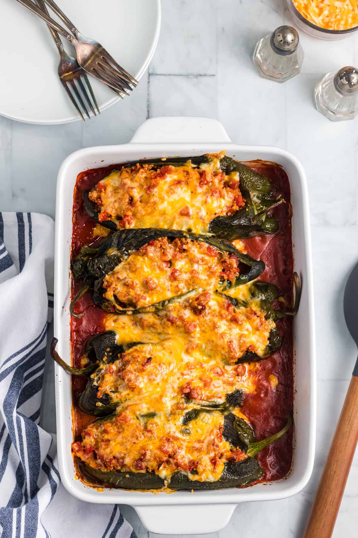 Four cooked stuffed peppers are arranged in a white baking dish.