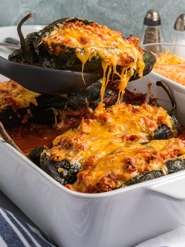 A pepper is being lifted from the baking dish.