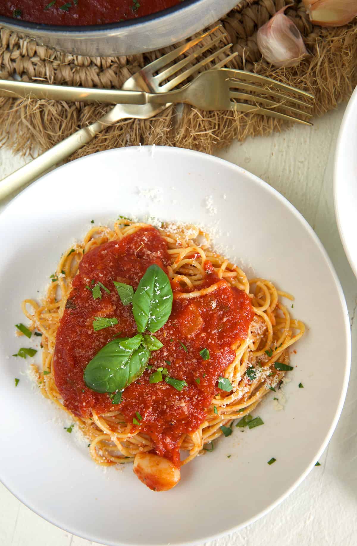 A white plate is topped with a serving of spaghetti and marinara sauce.