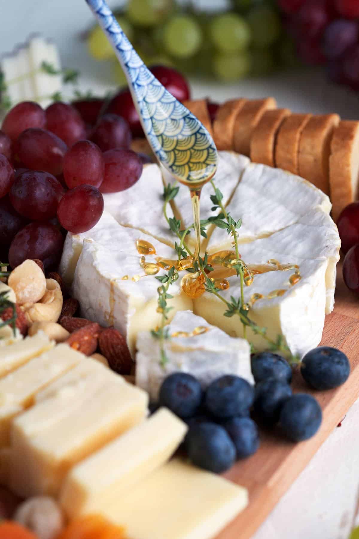 Drizzling honey onto cheese on cheese board