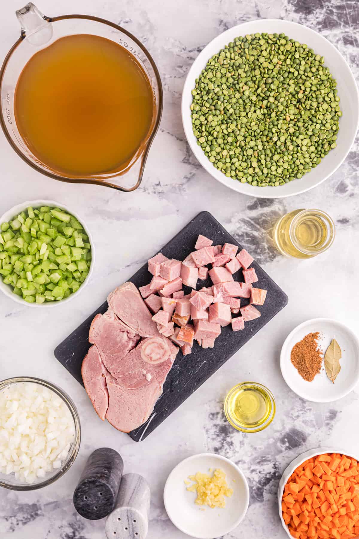 The ingredients for split pea soup with ham are presented on a white surface.