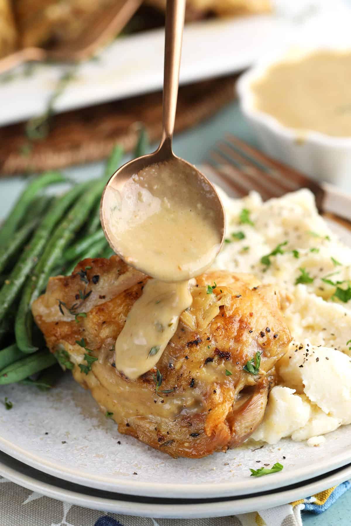 braised chicken thigh with a spoon drizzling sauce over it.