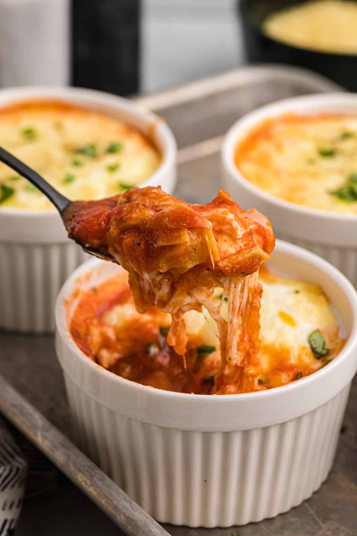 Italian Baked Eggs in a white ramekin with a spoon lifting some of the egg out of the dish.