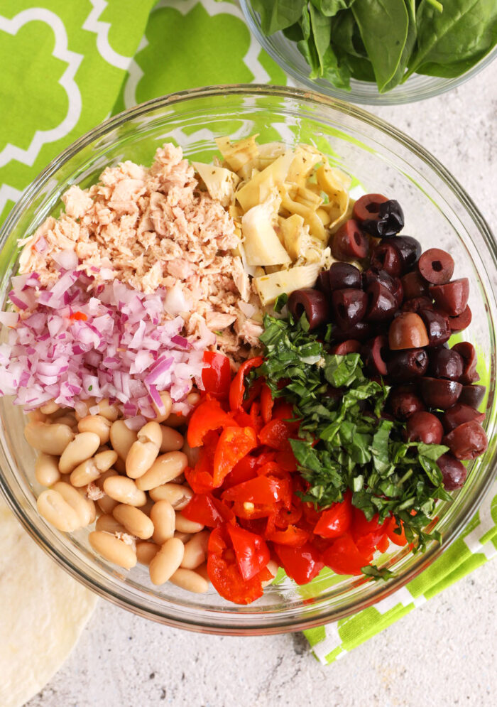 Overhead view of ingredients for Mediterranean tuna wrap filling in bowl