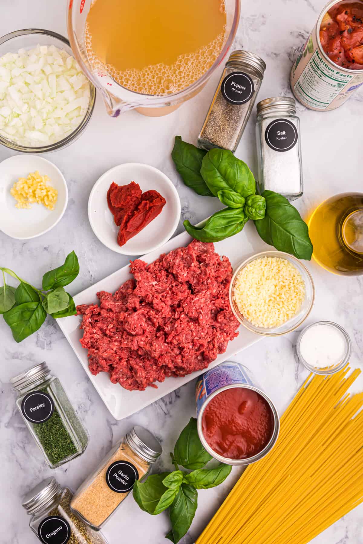 The ingredients for spaghetti and meatball stew are presented on a white surface.