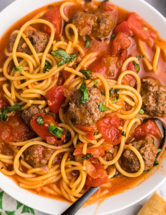A fork is placed in a large bowl of spaghetti and meatball stew.