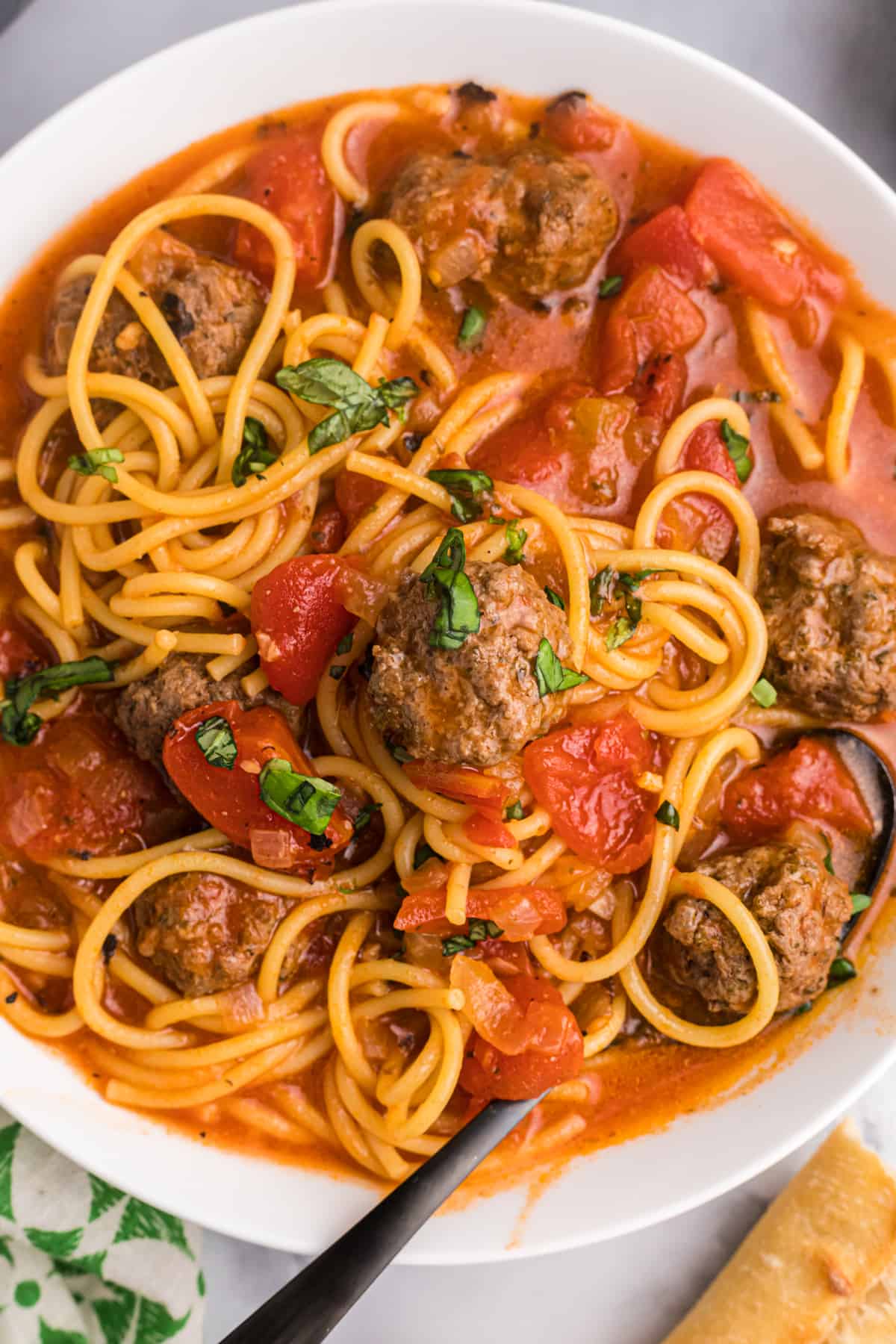 A fork is placed in a large bowl of spaghetti and meatball stew.