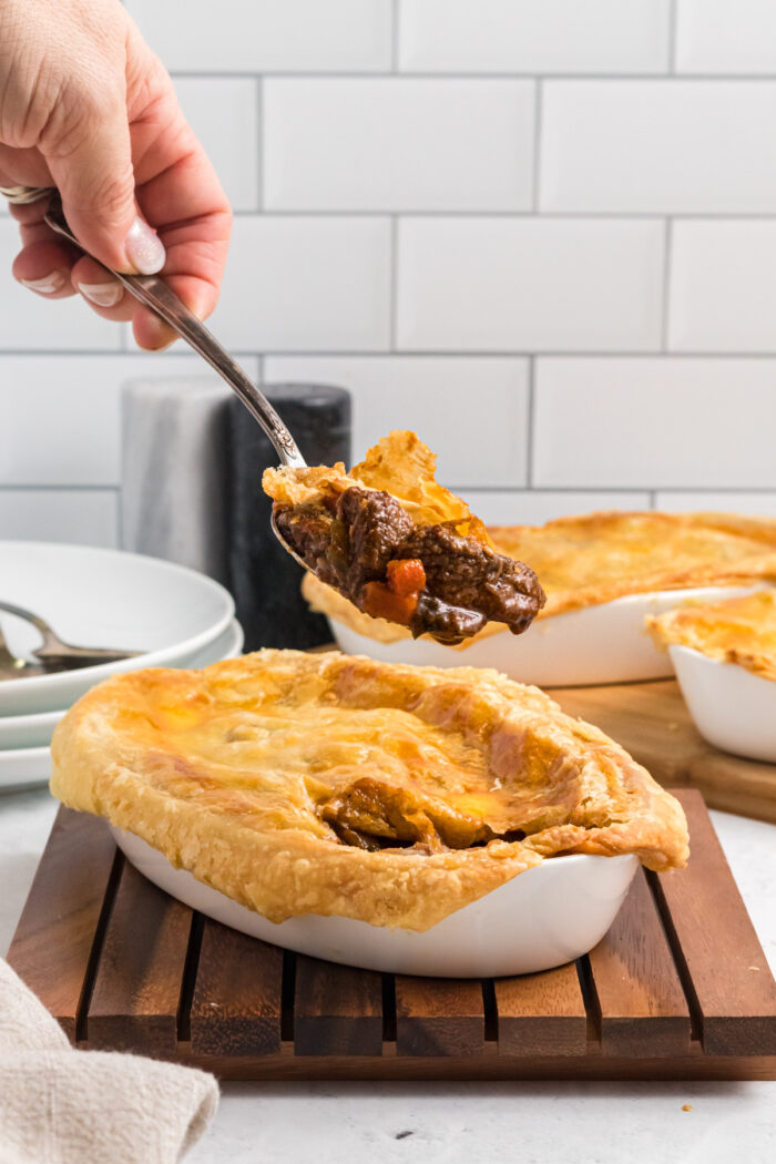 A portion of pot pie is being lifted from the whole serving.
