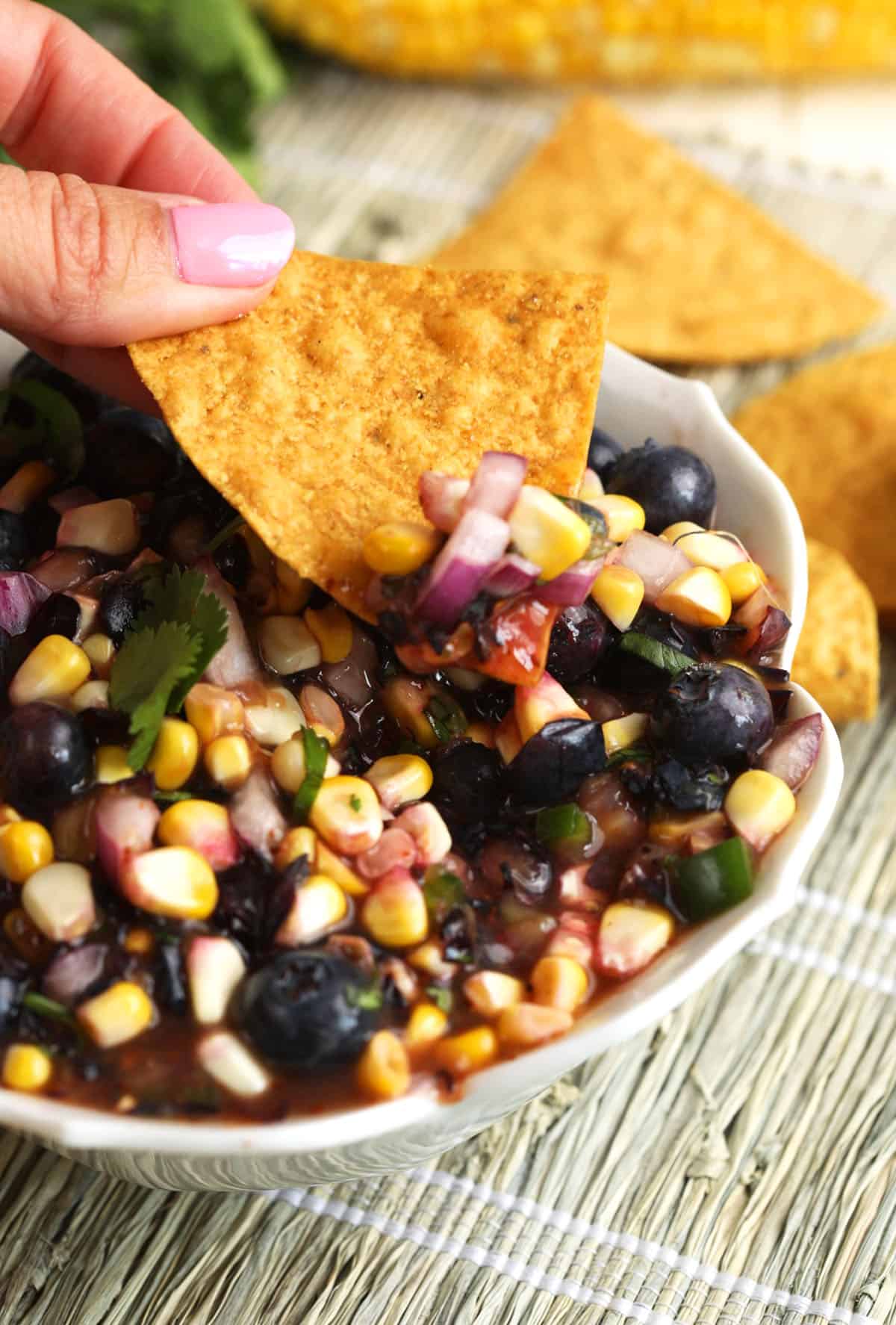 Dipping chip into blueberry corn salsa