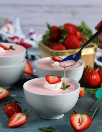 Strawberry Soup in a white bowl with a blue spoon drizzling from TheSuburbansoapbox.com