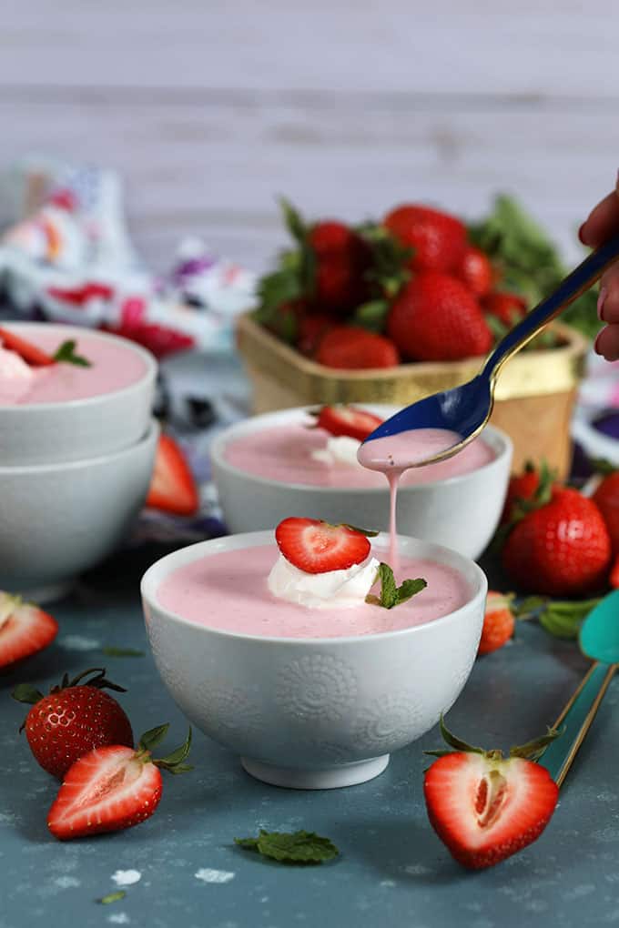 Strawberry Soup in a white bowl with a blue spoon drizzling from TheSuburbansoapbox.com