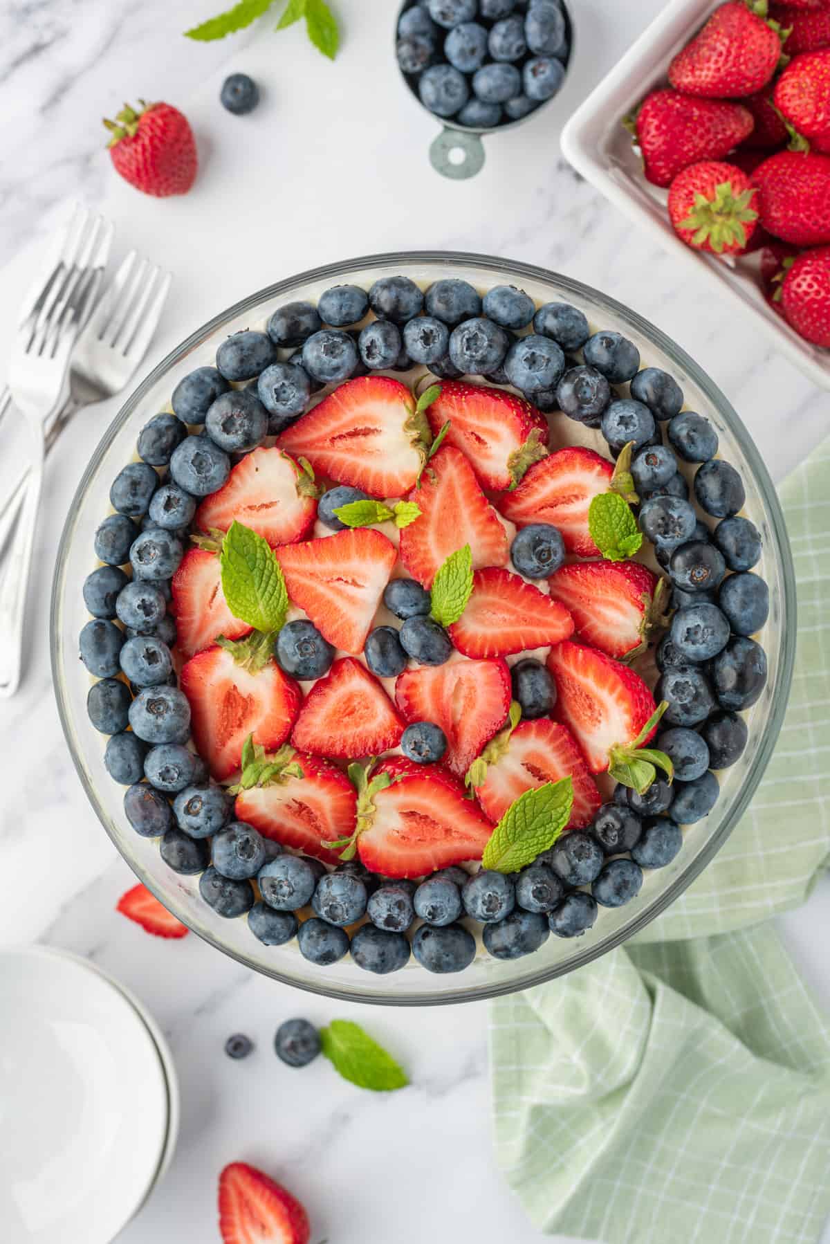 Blueberries and strawberries are placed on top of a trifle dish.