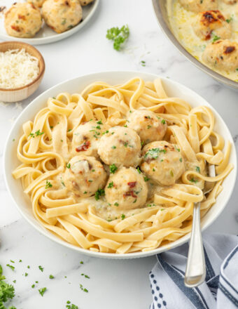 Meatballs and cream sauce are served over a big helping of pasta.
