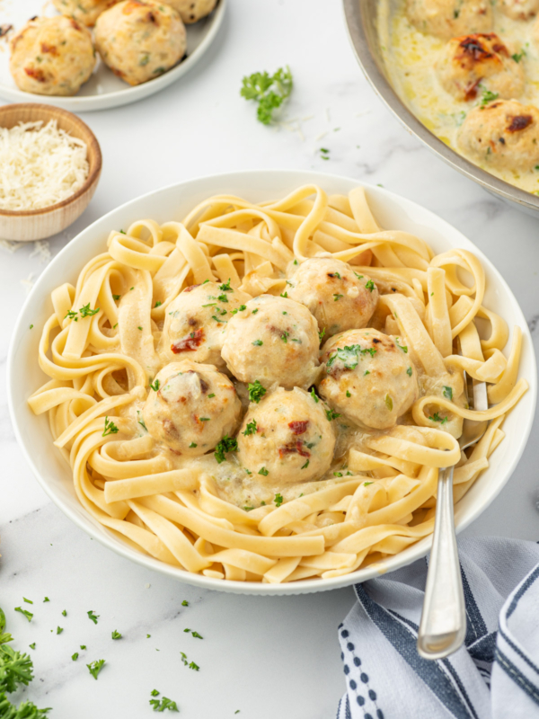 Meatballs and cream sauce are served over a big helping of pasta.