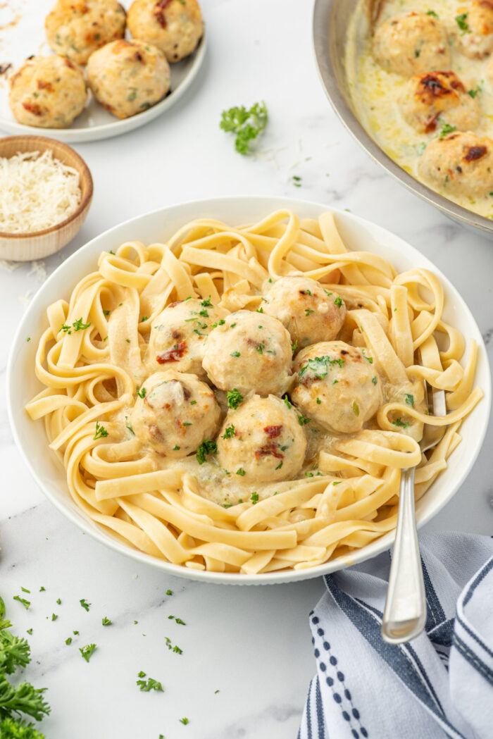 Meatballs and cream sauce are served over a big helping of pasta. 