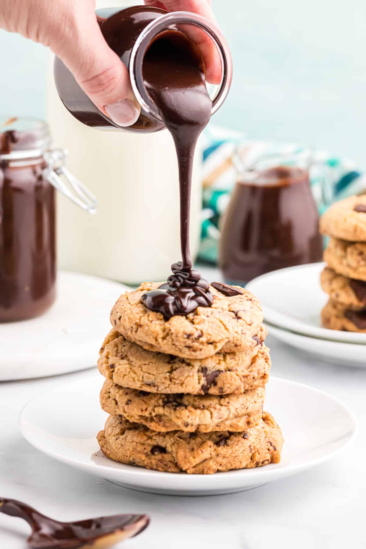 How fudge sauce is being poured onto a stack of cookies. 