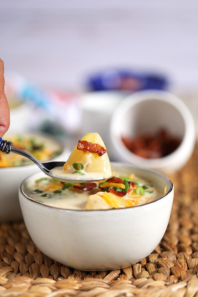 Spoonful of Loaded Baked Potato Soup over a white bowl.
