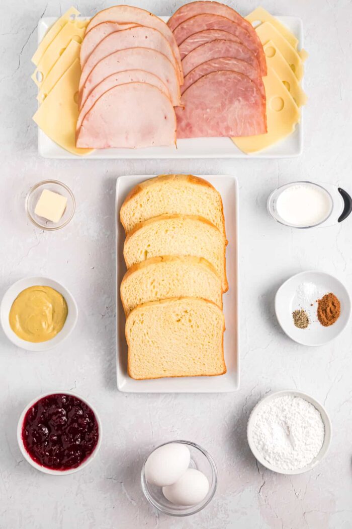 The ingredients for a monte cristo sandwich are placed on a white surface.