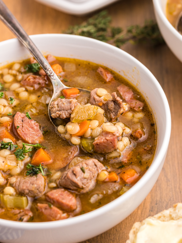 A spoon is digging into a bowl full of soup.