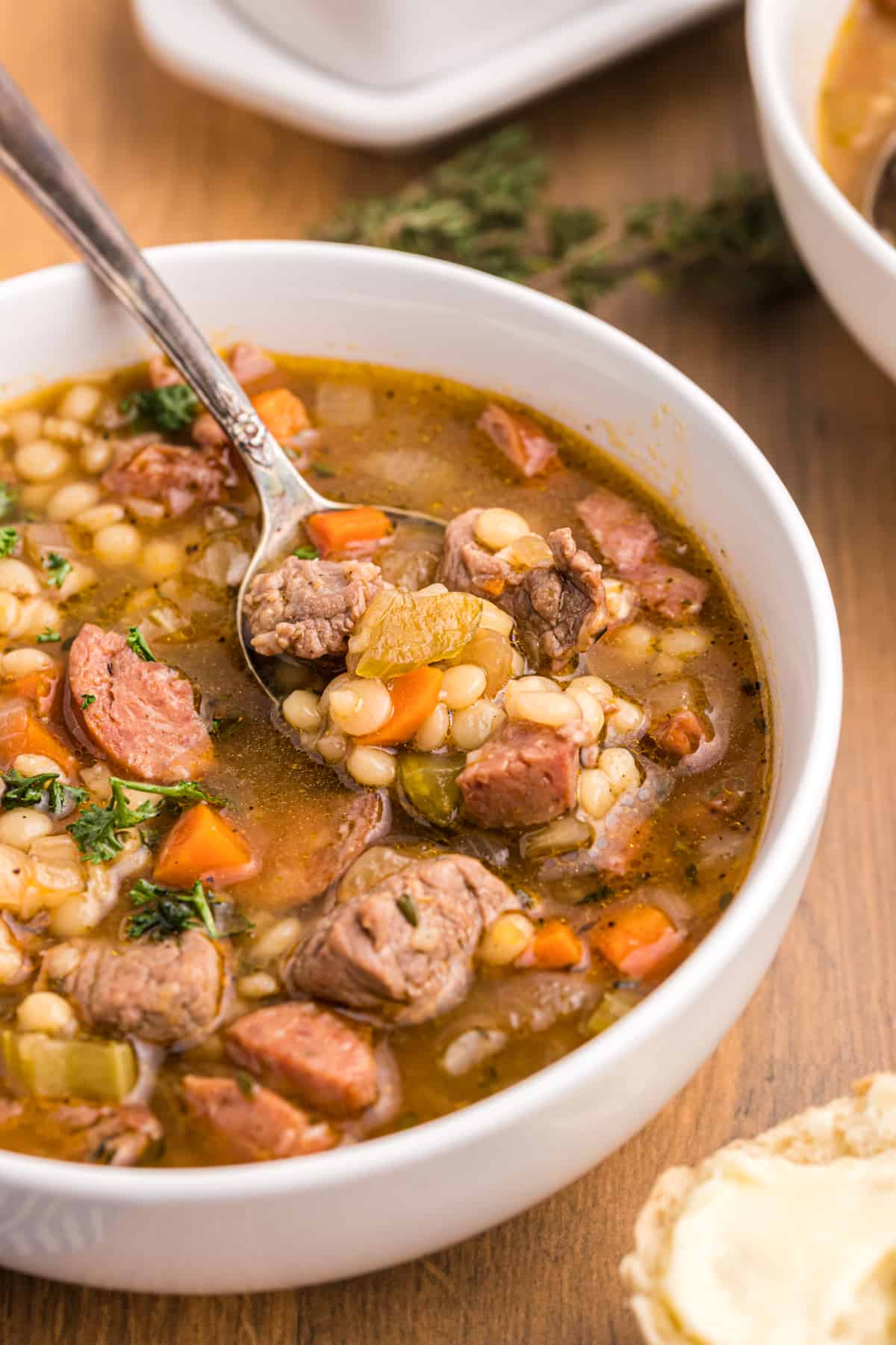 A spoon is digging right into a bowl chubby of soup.  Beef and Barley Soup with Andouille Sausage BeefBarleySoup 21