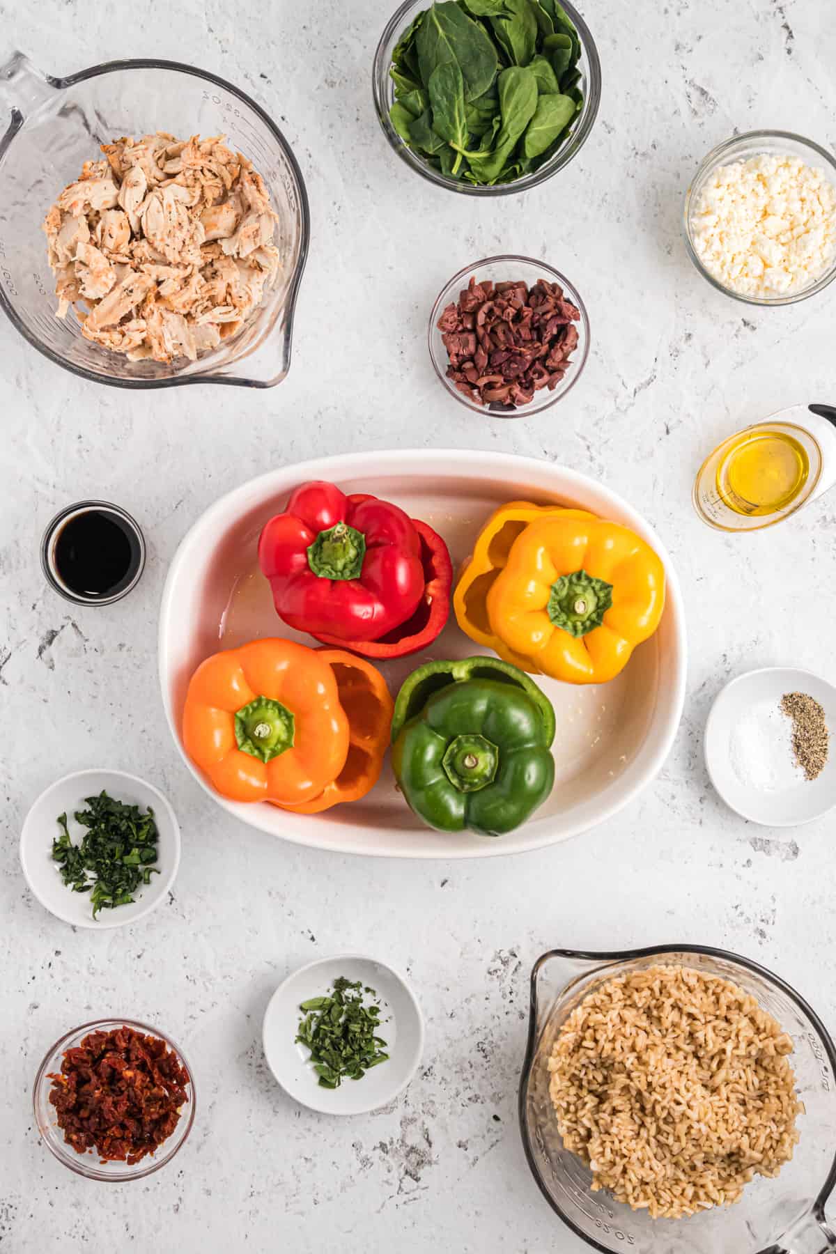 The ingredients for stuffed bell peppers are spread out across a white countertop.