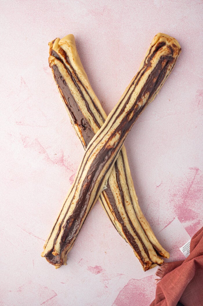 Overhead view of two logs of chocolate babka dough crossed