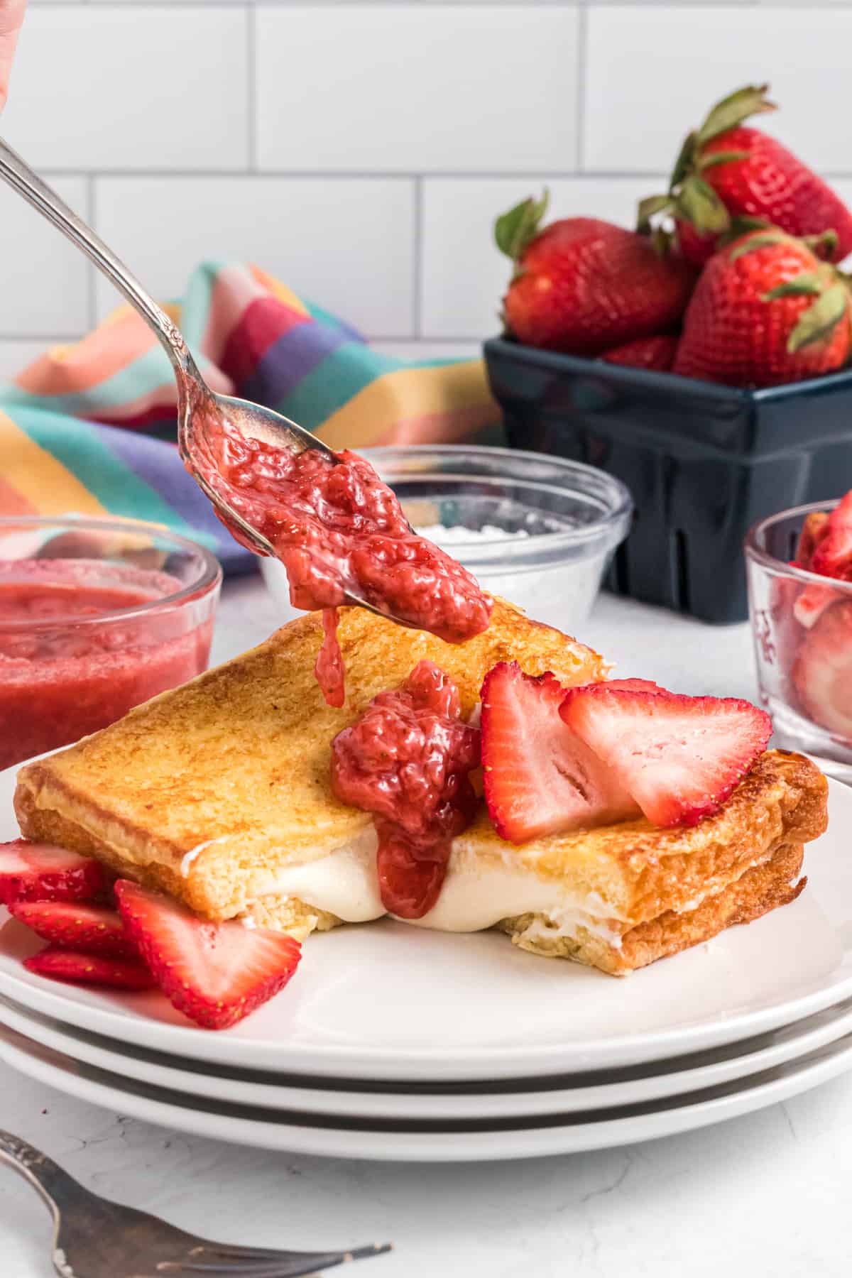 Starwberry compote is being drizzled atop a slice of stuffed french toast.