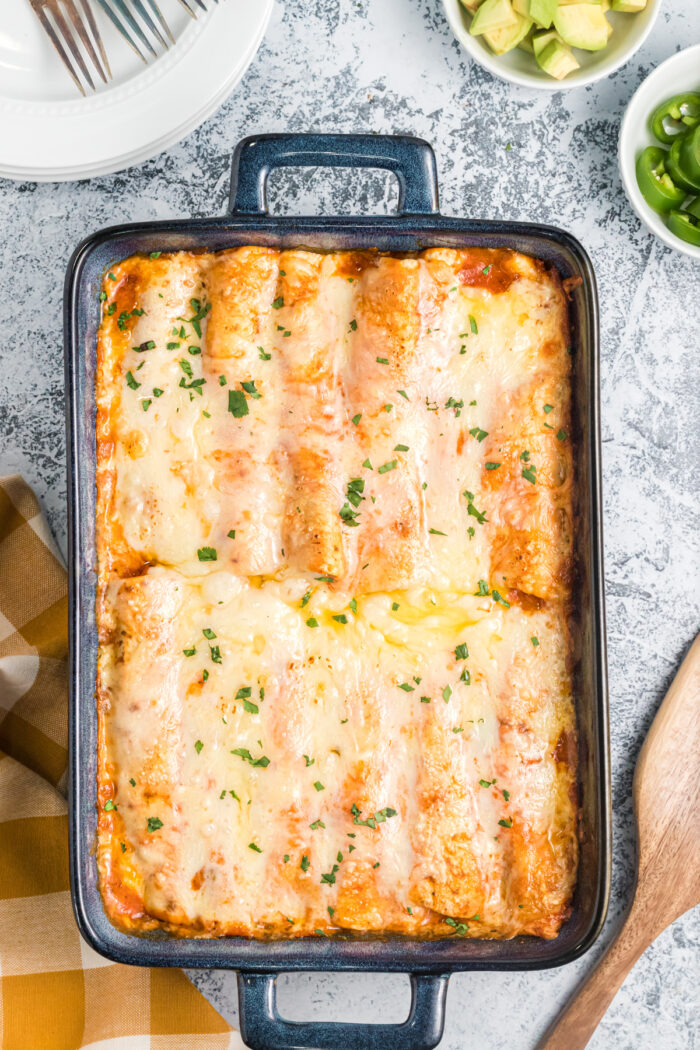 A casserole dish is full of cheesy baked enchiladas.
